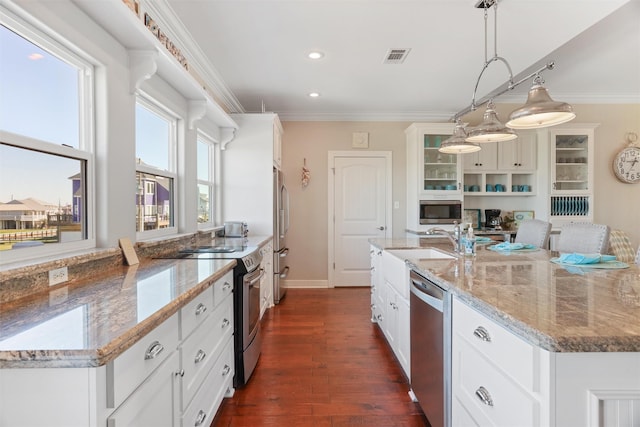 kitchen featuring appliances with stainless steel finishes, decorative light fixtures, glass insert cabinets, and light stone countertops