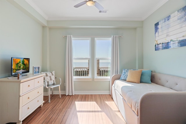 bedroom with a water view, light wood-style floors, visible vents, and crown molding