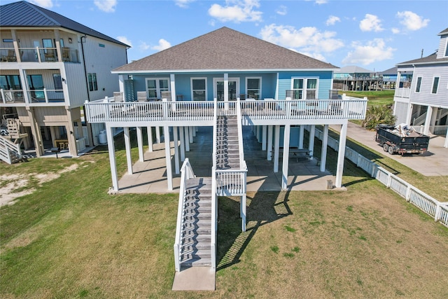 rear view of property featuring a lawn, a patio, roof with shingles, stairs, and fence