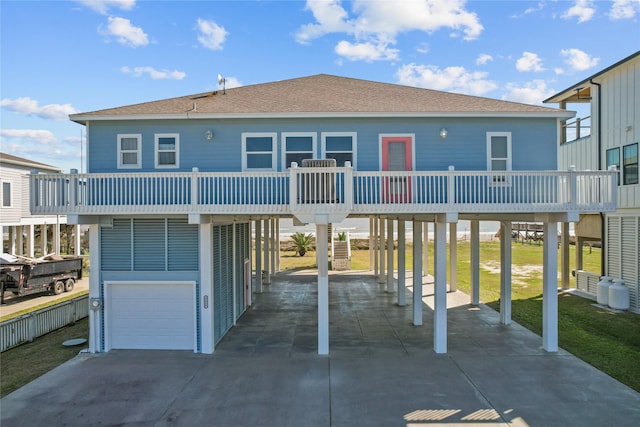 exterior space featuring a balcony, a garage, a shingled roof, driveway, and a carport