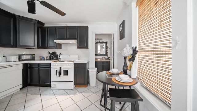 kitchen featuring under cabinet range hood, dark cabinetry, white appliances, light countertops, and light tile patterned floors