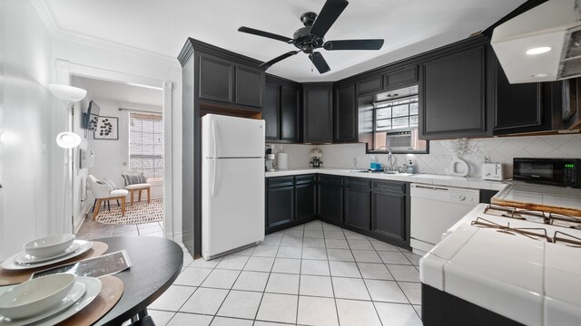 kitchen with a sink, white appliances, light tile patterned floors, tile counters, and dark cabinets