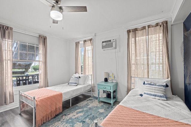 bedroom with a ceiling fan, wood finished floors, baseboards, a wall mounted AC, and crown molding