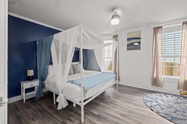 bedroom featuring baseboards, wood finished floors, and crown molding