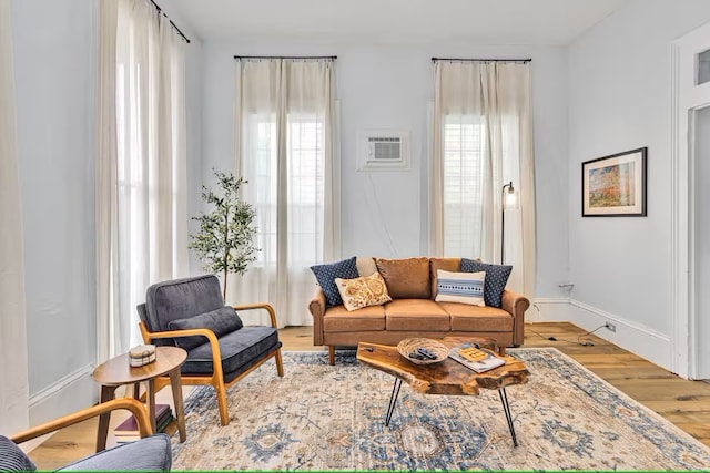 living room with baseboards, an AC wall unit, and wood finished floors