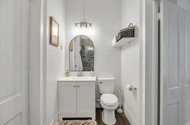 bathroom with tile walls, toilet, vanity, and wood finished floors