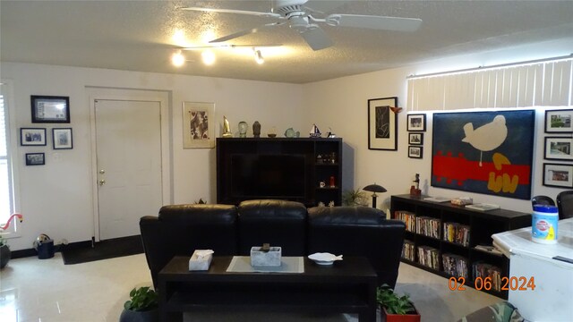 living room featuring ceiling fan and a textured ceiling