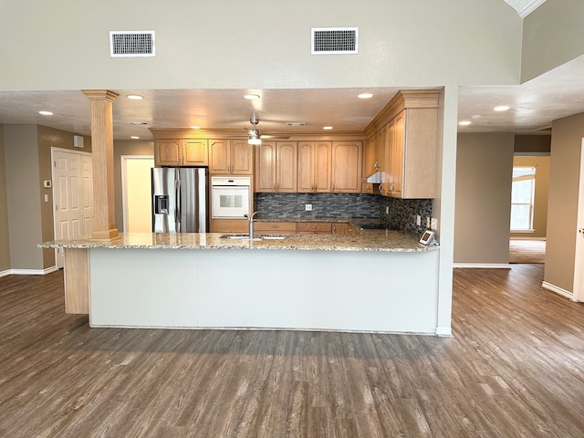 kitchen featuring oven, sink, stainless steel fridge, dark hardwood / wood-style floors, and light stone countertops