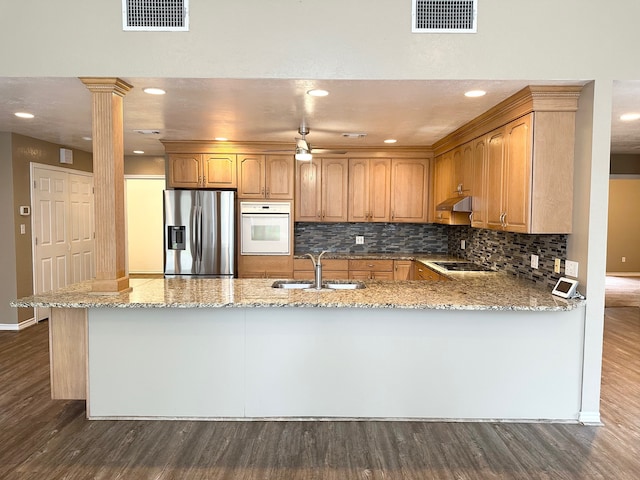 kitchen with dark wood-type flooring, sink, tasteful backsplash, white oven, and stainless steel fridge