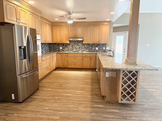 kitchen featuring light stone countertops, light hardwood / wood-style flooring, sink, stainless steel fridge, and ceiling fan