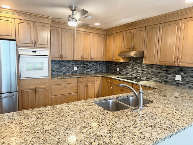 kitchen with backsplash, ceiling fan, oven, and stainless steel refrigerator