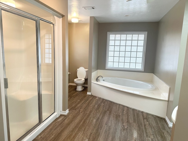 bathroom with hardwood / wood-style flooring, toilet, separate shower and tub, and a textured ceiling