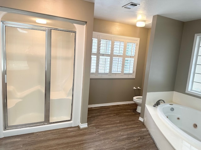 bathroom with wood-type flooring, independent shower and bath, toilet, and a textured ceiling