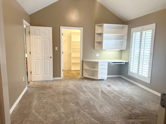 unfurnished bedroom featuring light carpet, a walk in closet, and lofted ceiling