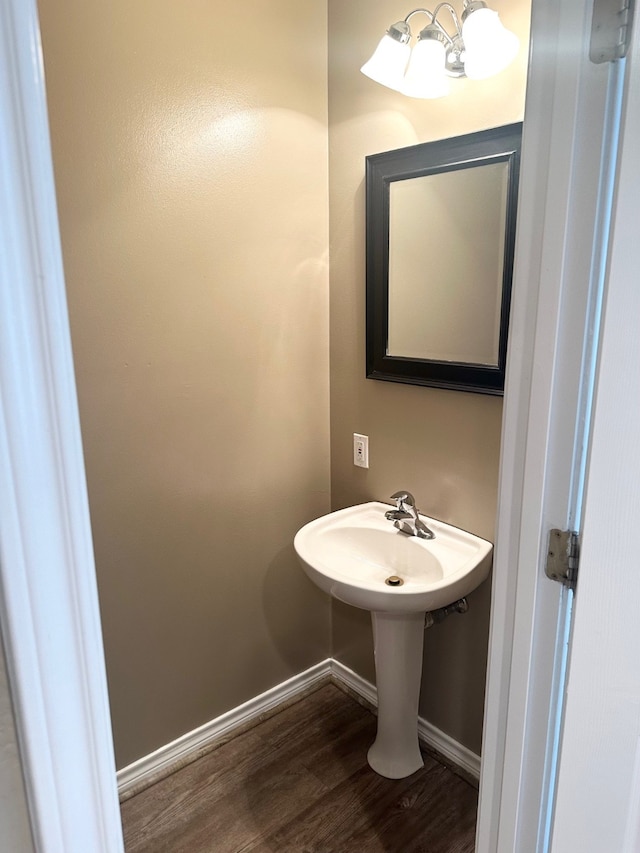 bathroom with hardwood / wood-style flooring and a notable chandelier