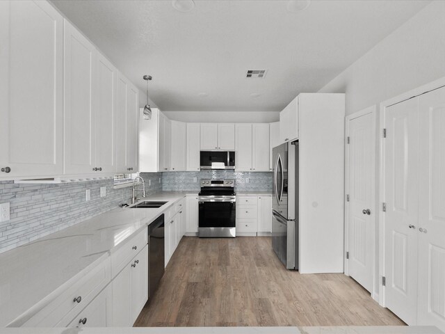 kitchen featuring decorative light fixtures, appliances with stainless steel finishes, light hardwood / wood-style floors, and sink