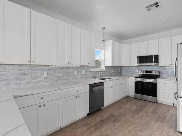 kitchen featuring appliances with stainless steel finishes, decorative backsplash, sink, and light hardwood / wood-style flooring