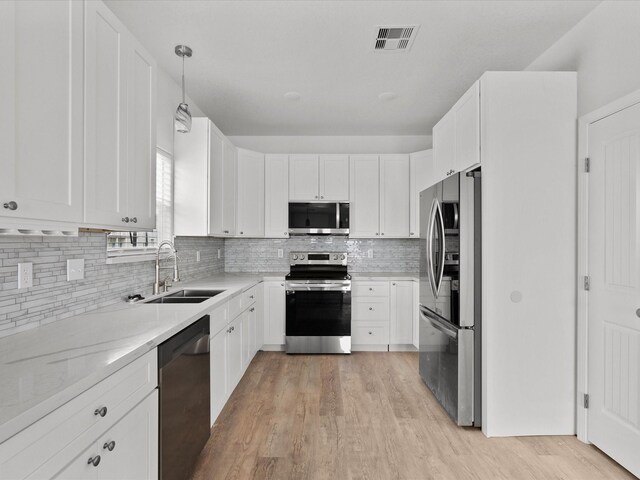 kitchen featuring stainless steel appliances, sink, tasteful backsplash, and light hardwood / wood-style floors