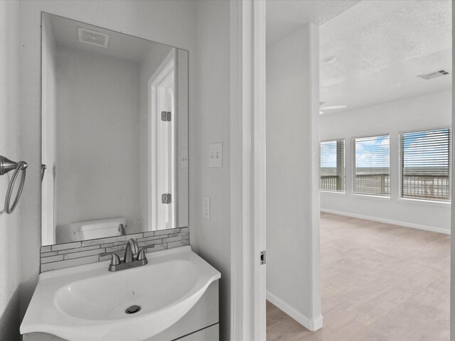 bathroom featuring vanity, toilet, backsplash, and a textured ceiling