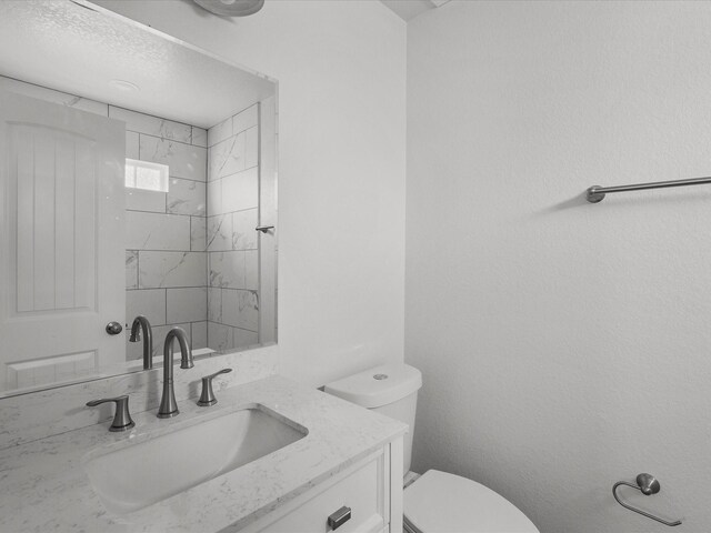 bathroom featuring vanity, toilet, and a tile shower