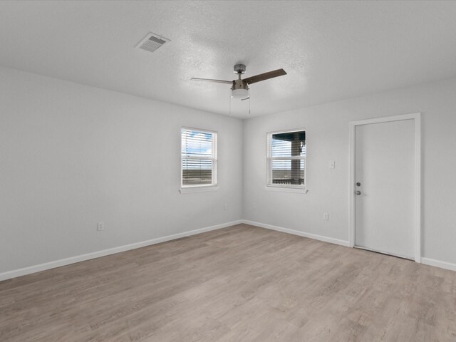 empty room with a textured ceiling, ceiling fan, and light wood-type flooring