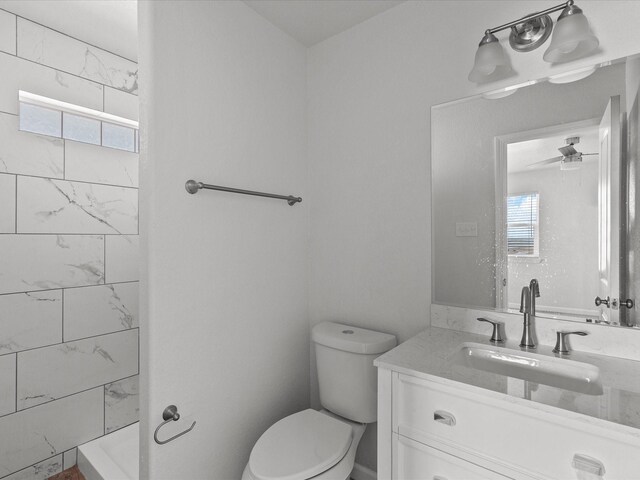 bathroom with tiled shower, toilet, and vanity