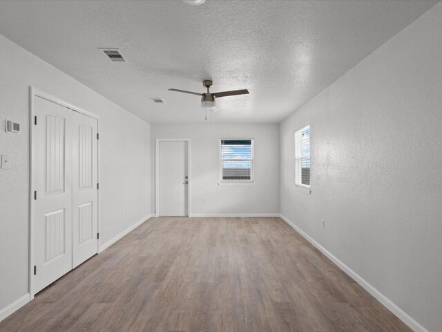 spare room with hardwood / wood-style floors, ceiling fan, and a textured ceiling