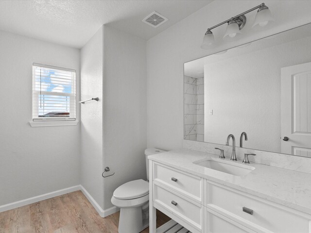 bathroom featuring vanity, toilet, hardwood / wood-style floors, and a textured ceiling