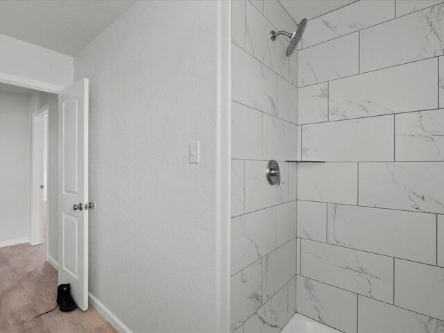 bathroom featuring hardwood / wood-style flooring and a tile shower