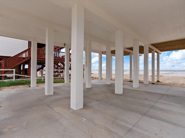 view of patio with a beach view and a deck with water view