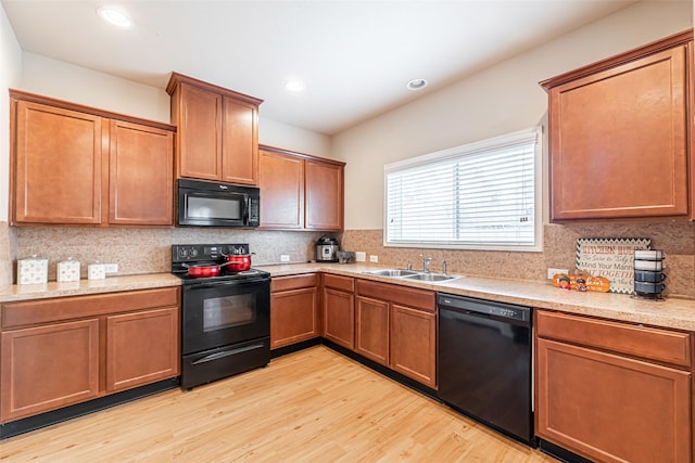 kitchen featuring decorative backsplash, sink, black appliances, and light wood-type flooring