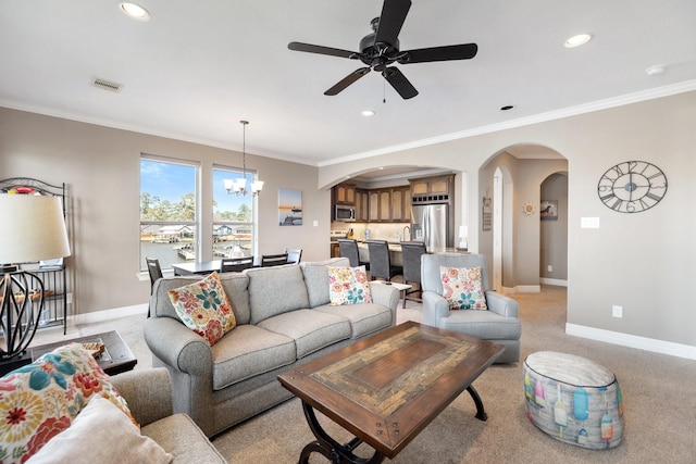 living room featuring light colored carpet, ceiling fan with notable chandelier, and ornamental molding