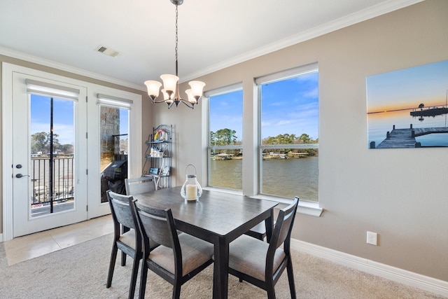 carpeted dining room featuring crown molding, a chandelier, and a water view