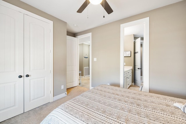 bedroom with connected bathroom, light carpet, ceiling fan, and a closet