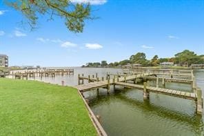 view of dock with a yard and a water view