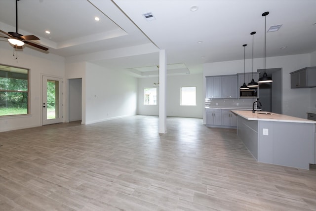 kitchen featuring stainless steel microwave, plenty of natural light, a tray ceiling, and gray cabinetry