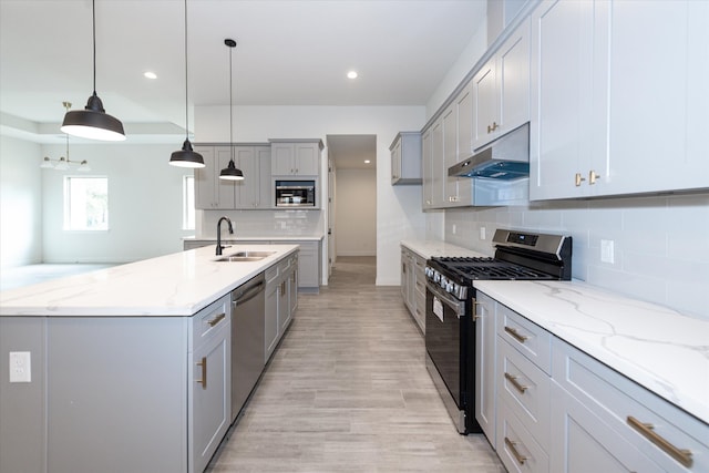 kitchen featuring hanging light fixtures, light hardwood / wood-style floors, sink, stainless steel appliances, and tasteful backsplash