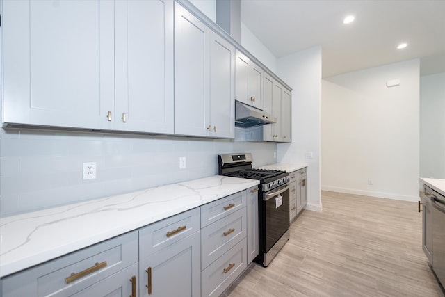 kitchen featuring light stone countertops, gray cabinetry, backsplash, appliances with stainless steel finishes, and light wood-type flooring