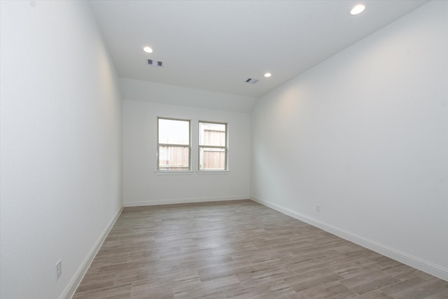 unfurnished room with lofted ceiling and light hardwood / wood-style floors