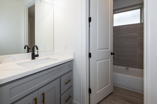 bathroom with tiled shower / bath combo, vanity, and wood-type flooring