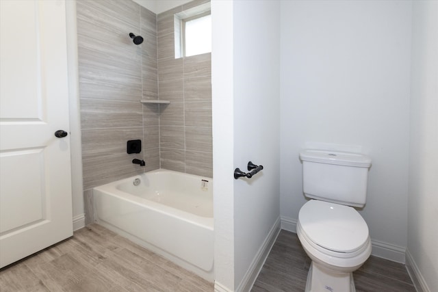 bathroom featuring toilet, tiled shower / bath combo, and wood-type flooring