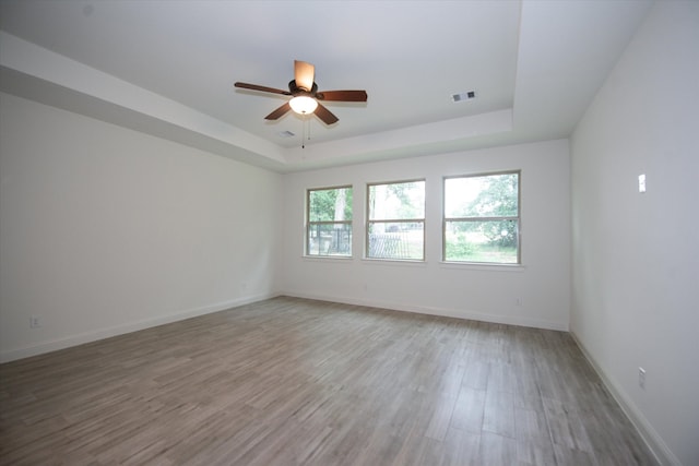 spare room featuring ceiling fan, light hardwood / wood-style floors, and a raised ceiling