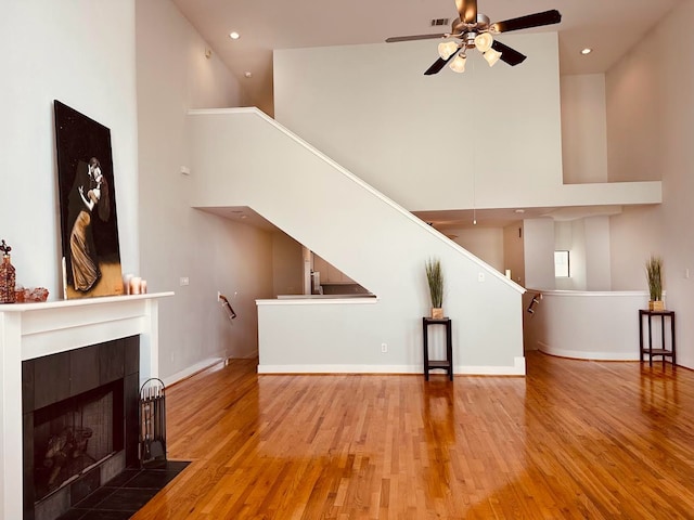 living room with a towering ceiling, hardwood / wood-style floors, and ceiling fan