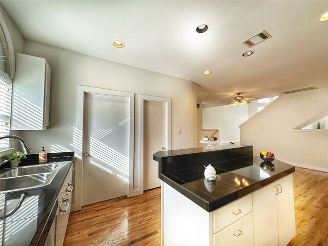 kitchen featuring sink, white cabinets, ceiling fan, and light wood-type flooring