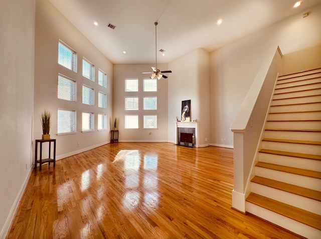 unfurnished living room featuring light wood-type flooring, ceiling fan, and a wealth of natural light