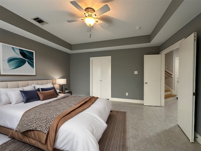 tiled bedroom featuring ceiling fan and a raised ceiling