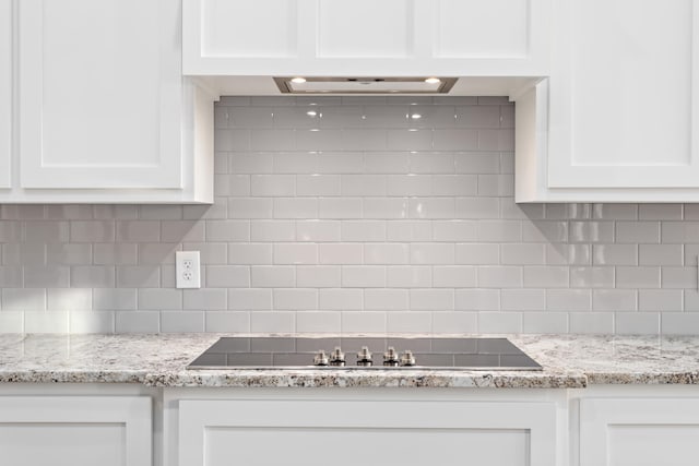 kitchen featuring light stone countertops, tasteful backsplash, and white cabinets