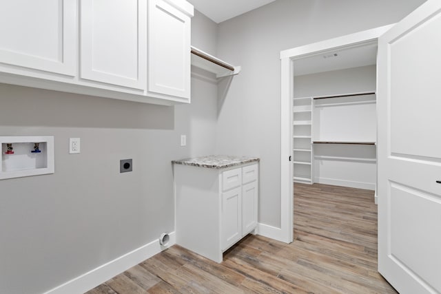 clothes washing area with washer hookup, electric dryer hookup, light hardwood / wood-style flooring, and cabinets