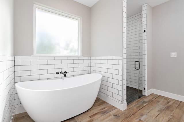 bathroom featuring hardwood / wood-style floors, independent shower and bath, and tile walls