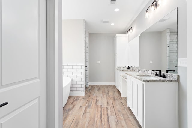 bathroom with a bath, hardwood / wood-style flooring, and dual bowl vanity